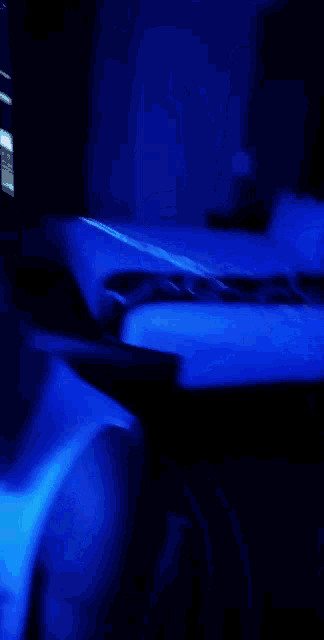 a bald man in a white tank top is surrounded by blue light