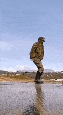 a man in a military uniform is standing in a puddle .