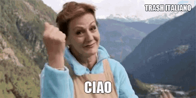 a woman is giving a thumbs up in front of a mountain range .