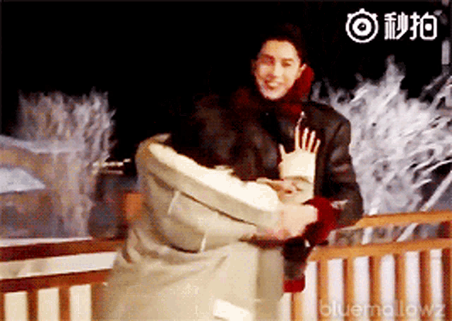 a man is holding a woman in his arms in front of a sign that says bluemallow
