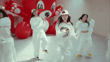 a group of young women are dancing in front of an inflatable teddy bear