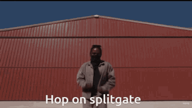 a man standing in front of a red building with the words hop on splitgate