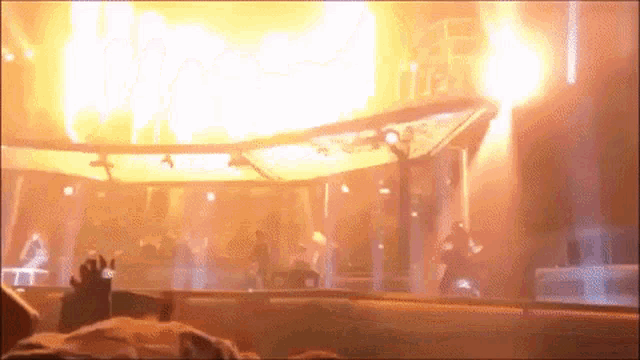 a crowd of people watching a stage with flames coming out
