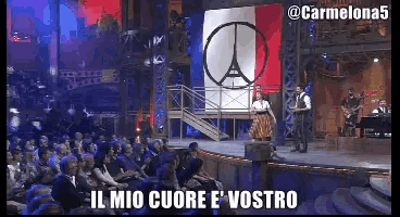a group of people sitting in front of a stage with the words il mio cuore e vostro on it