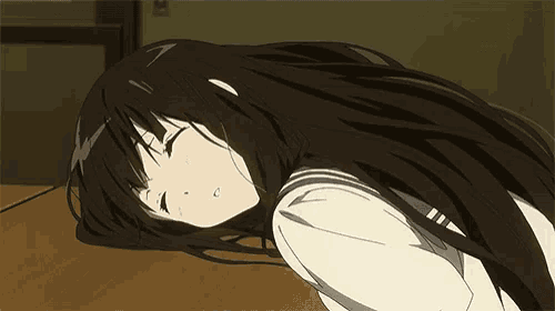 a girl with long black hair is laying on a wooden floor with her eyes closed .