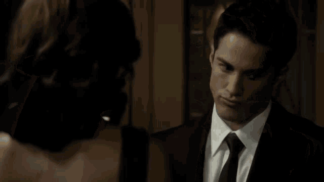 a man in a suit and tie is standing next to a woman .