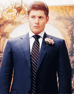 a man in a suit and tie with a flower in his lapel