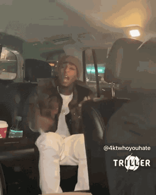 a man is sitting in the back seat of a car with a triller logo