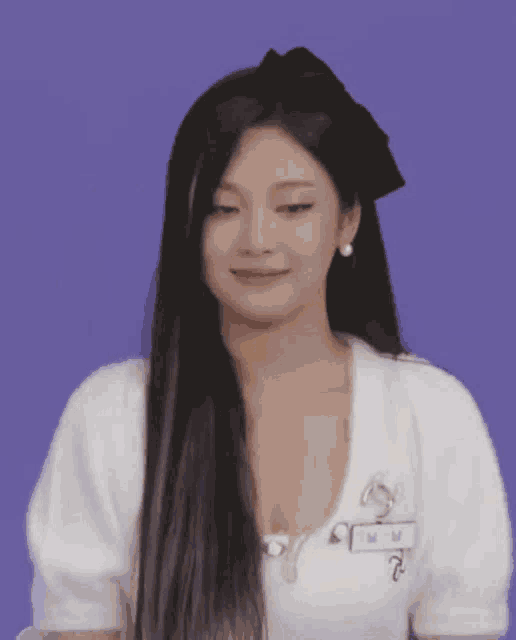 a woman with long hair and a bow in her hair is wearing a white shirt and earrings .