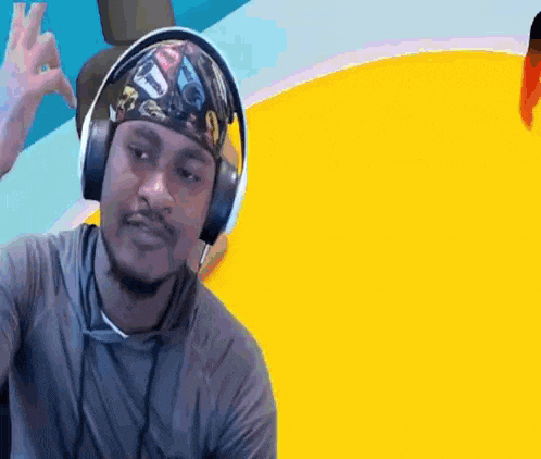 a man wearing headphones and a bandana is making a peace sign .