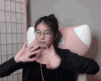 a woman wearing glasses is sitting in a pink chair with the letter b on the back