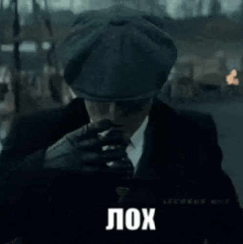 a man in a suit and tie is wearing a hat and sunglasses and says lox in russian .
