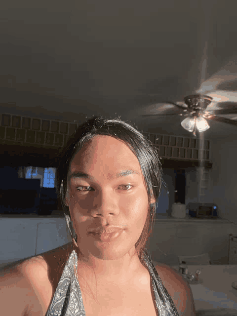 a woman taking a selfie with a ceiling fan behind her