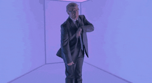 a man in a suit and tie is making a funny face while standing in front of a window .