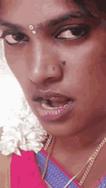 a close up of a woman 's face with a nose ring and a necklace