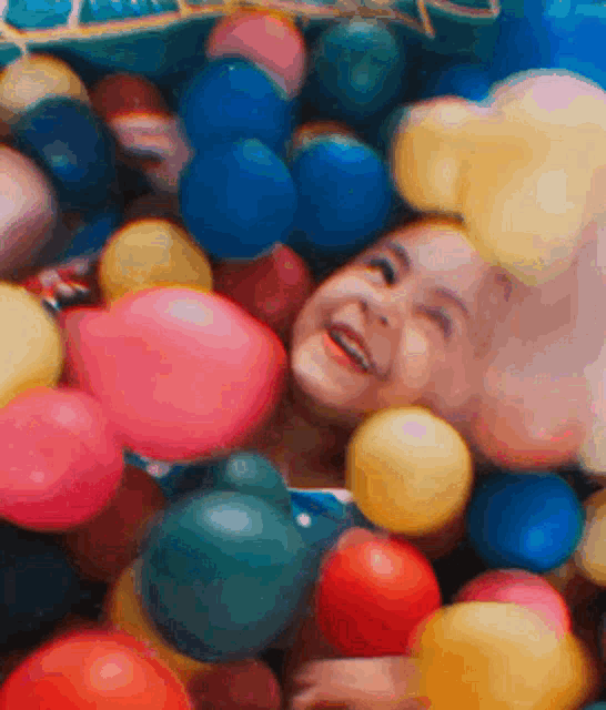 a child is laying in a pile of balloons