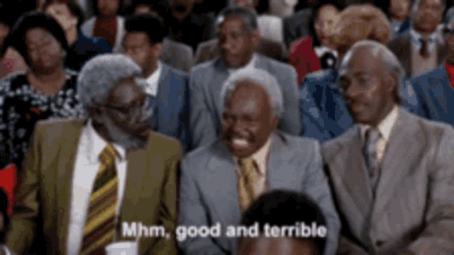 a group of men in suits and ties are sitting in a crowd and one of them is laughing and saying mhm good and terrible