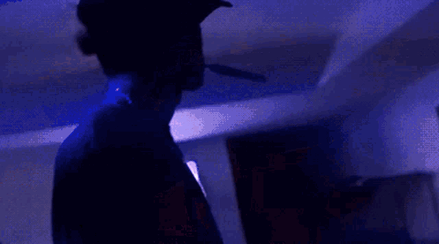 a man in a baseball cap is smoking a cigarette in a dark room