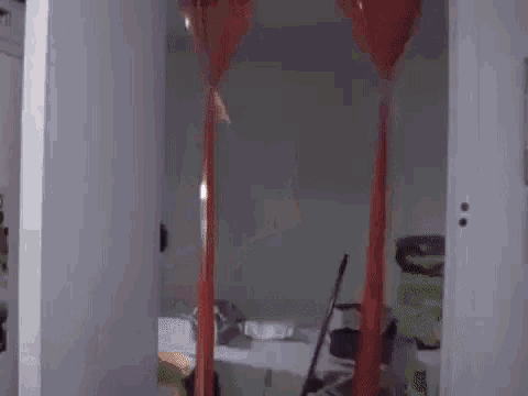 a man is standing in a room with balloons hanging from the ceiling and a mop .