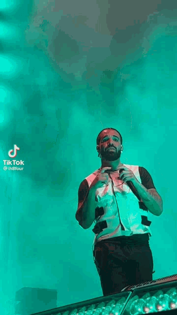 a man is standing on a stage with his arms outstretched in front of a microphone .