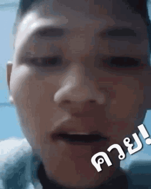 a close up of a young man 's face with a foreign language sticker on his face .