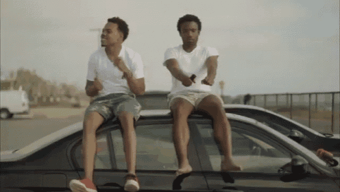 two men sit on the roof of a car