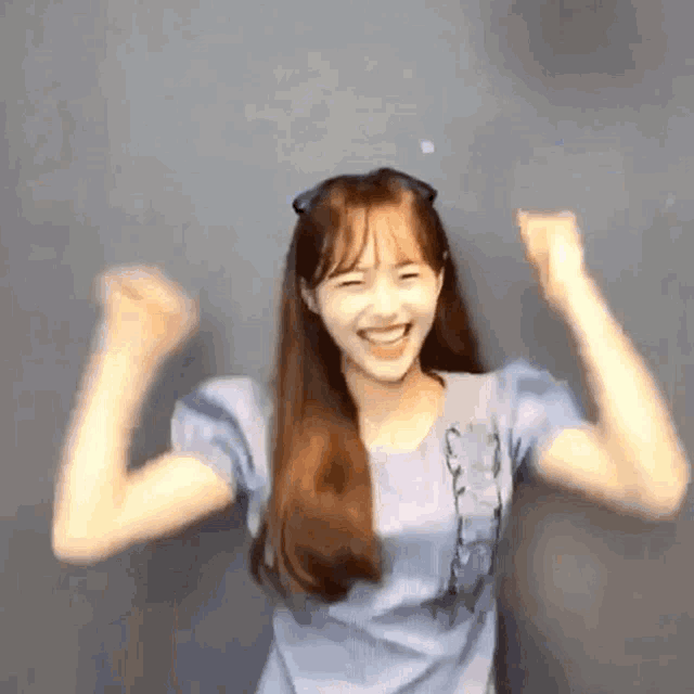 a girl in a blue shirt is raising her arms in the air .