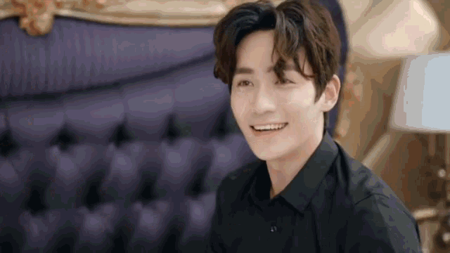 a young man in a black shirt is smiling