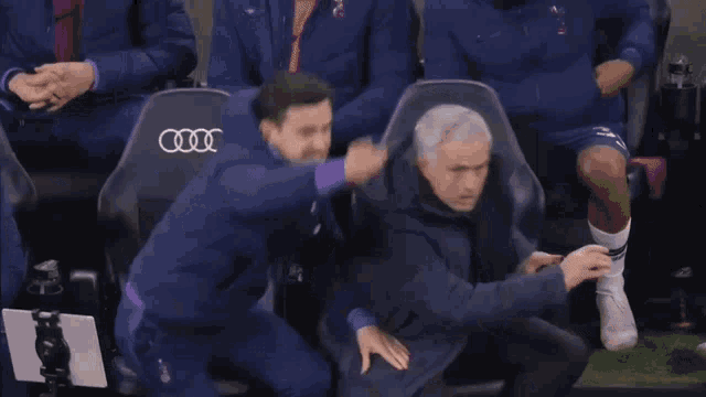 a man in a blue jacket is being held by a man in a black shirt .