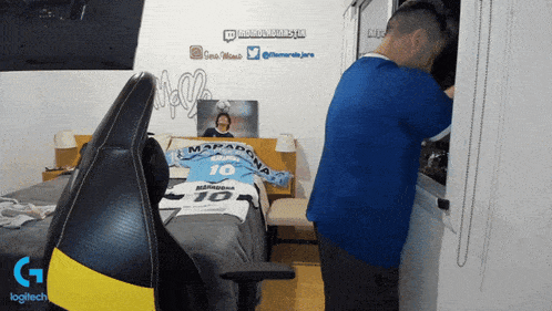 a man in a blue shirt with the number 10 on it stands next to a bed