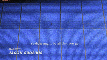 a man sits in a row of blue seats with hannah waddingham written in the corner