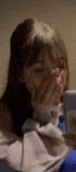 a woman is covering her face with her hands while looking at her phone .