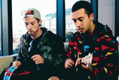 a man playing a guitar while another man looks on