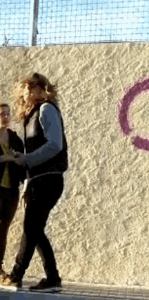 a couple of people standing in front of a wall with a purple circle painted on it