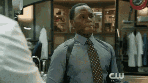 a man in a blue shirt and tie is talking to another man in a room .