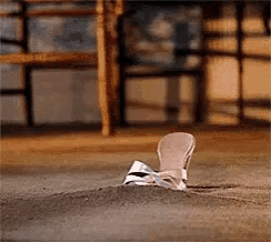a shoe is laying on a pile of dirt on the floor