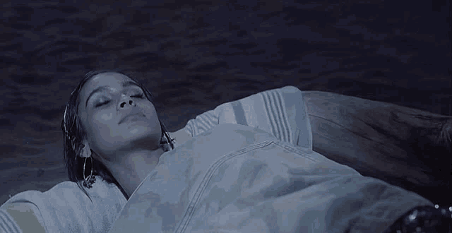 a woman is laying on a beach looking up
