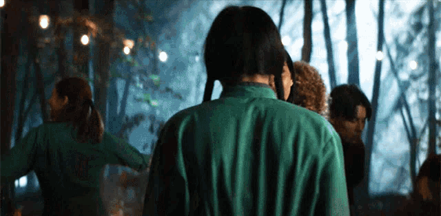 a man in a green shirt is standing in a forest