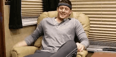 a man is sitting in a chair with his legs crossed and a headband on .