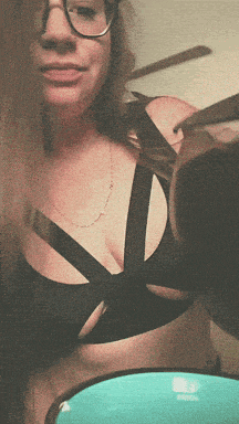 a woman wearing glasses is holding a pair of scissors in her hand