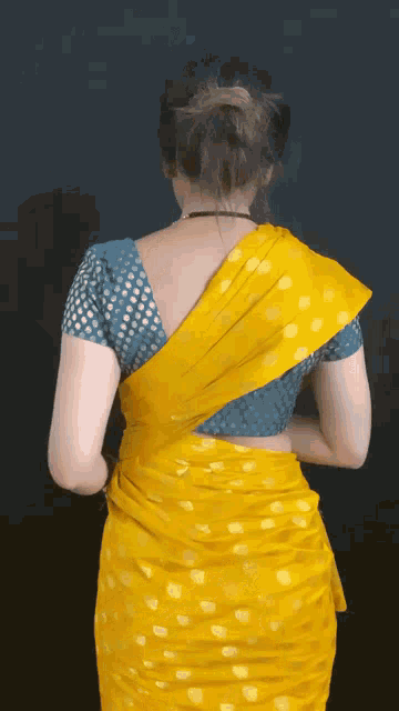 the back of a woman wearing a yellow saree
