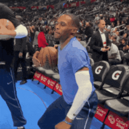 a man in a blue shirt is holding a basketball in front of a gatorade advertisement
