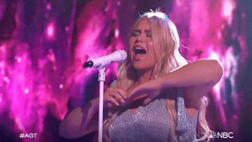 a woman singing into a microphone with nbc written on the bottom