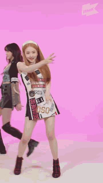 a girl in a dress with stickers on it is dancing on a pink background
