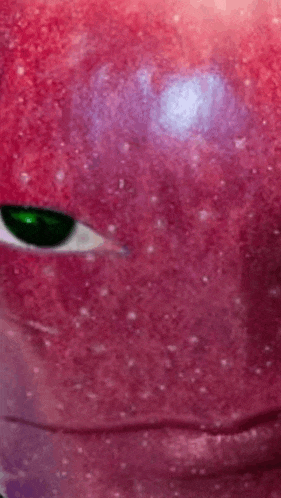 a close up of a pink apple with a green eye .