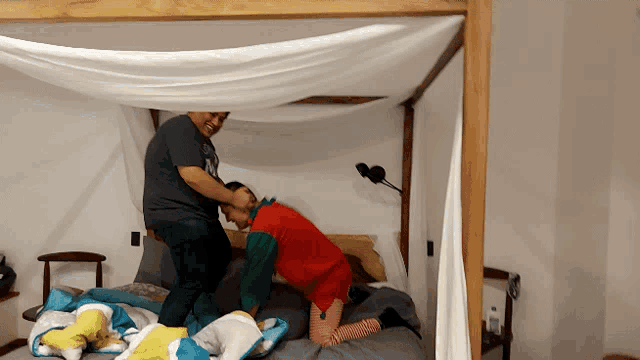 a man in a gray shirt is kneeling down on a bed