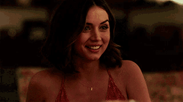 a woman in a red dress is smiling while looking at a pizza .