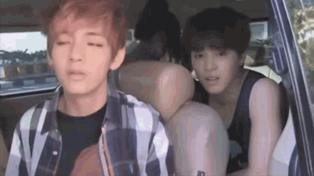 two young men are sitting in the back of a car .