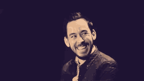 a man with a beard is laughing with his arms crossed