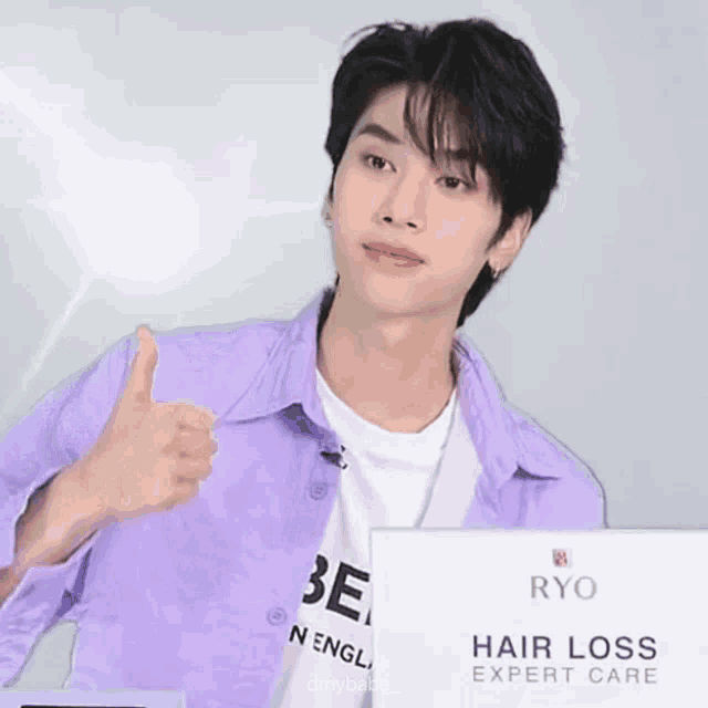 a young man is giving a thumbs up in front of a sign that says hair loss expert care